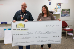 Two people standing in front of a check, smiling at the camera.