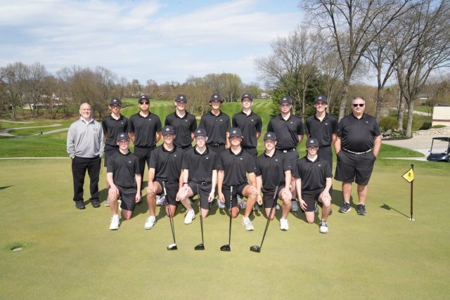 Golf team posing for a picture on a golf course.