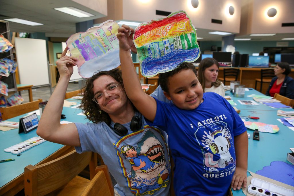 Penn student with 2nd Grade Student holding art