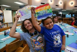 Penn student with 2nd Grade Student holding art