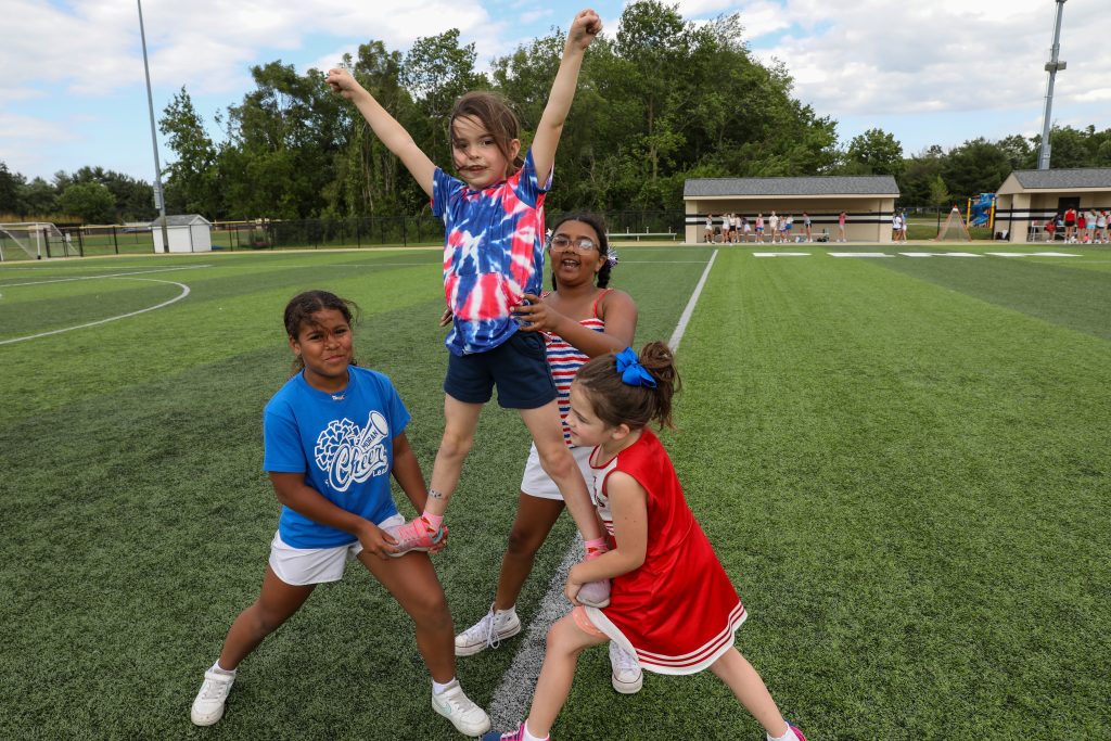 Five children posing on a soccer field.