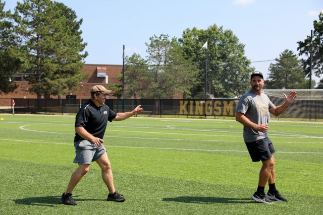 Two men walking on a football field.