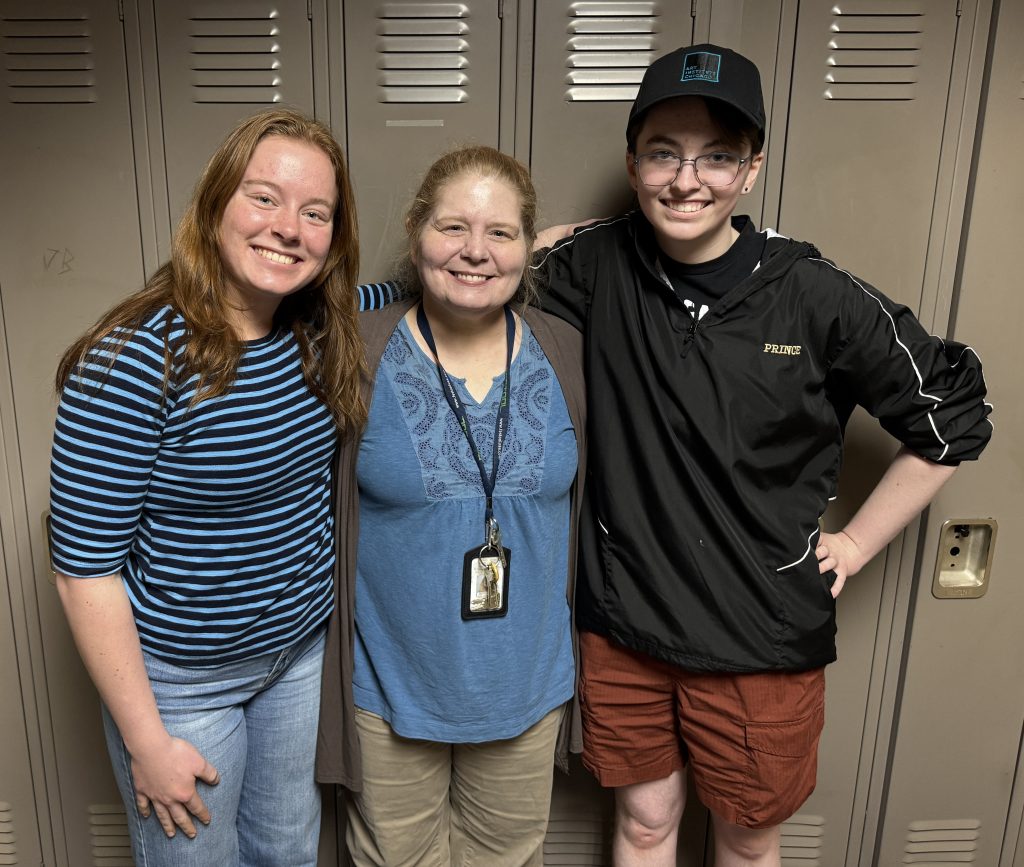 Three people posing in front of a locker.