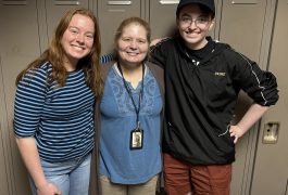 Three people posing in front of a locker.