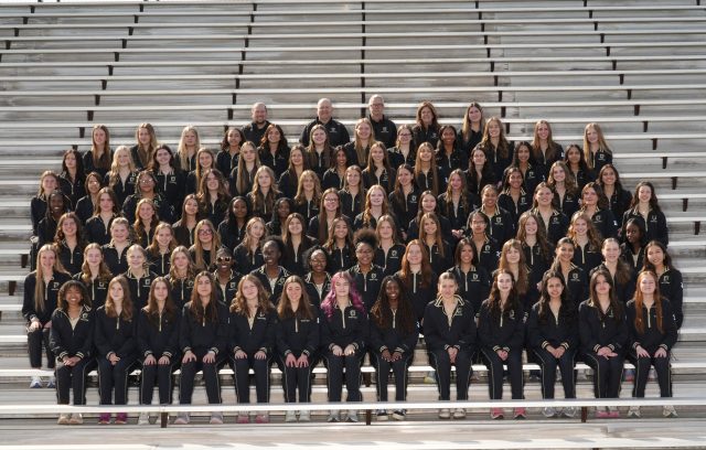 Girls Track & Field team members pose for a team picture on bleachers.