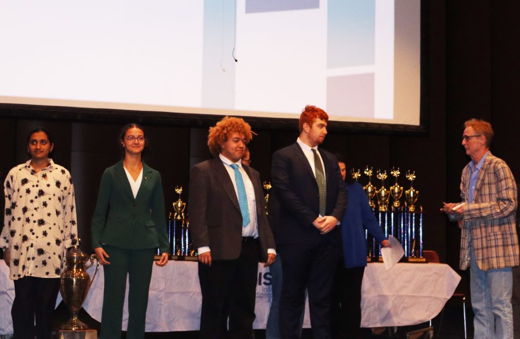Students standing on stage at the Speech State Tournament, receiving awards.