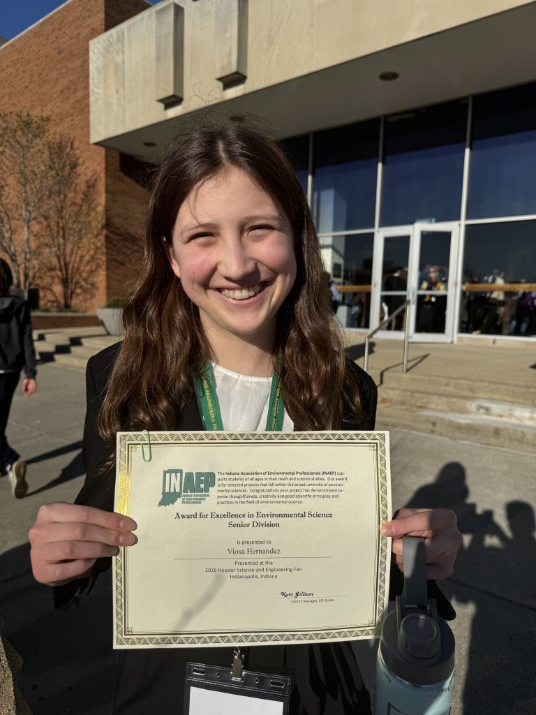 Girl holding a certificate in front of a building.