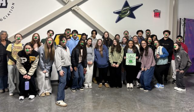 Group of people posing in front of a wall.