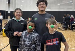 Four people posing for a picture on an indoor court.
