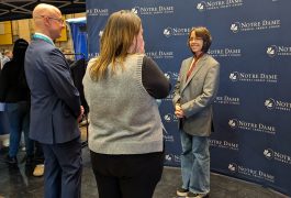 People standing in front of a booth at an event, engaging in conversation.