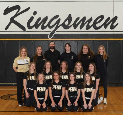 A team of Softball players posing for a picture in front of a banner that reads
