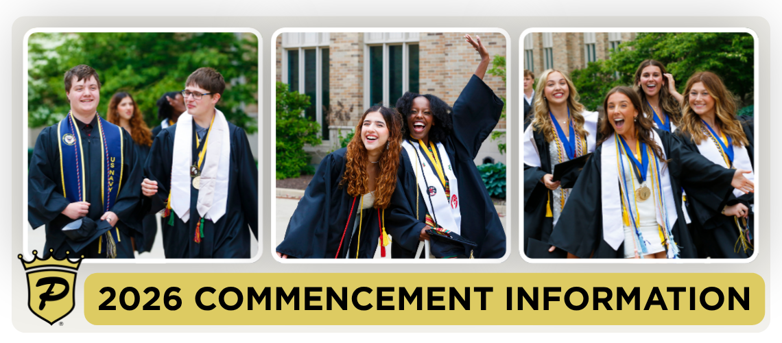 Group of students celebrating commencement, posing for a group photo in front of a building with trees.