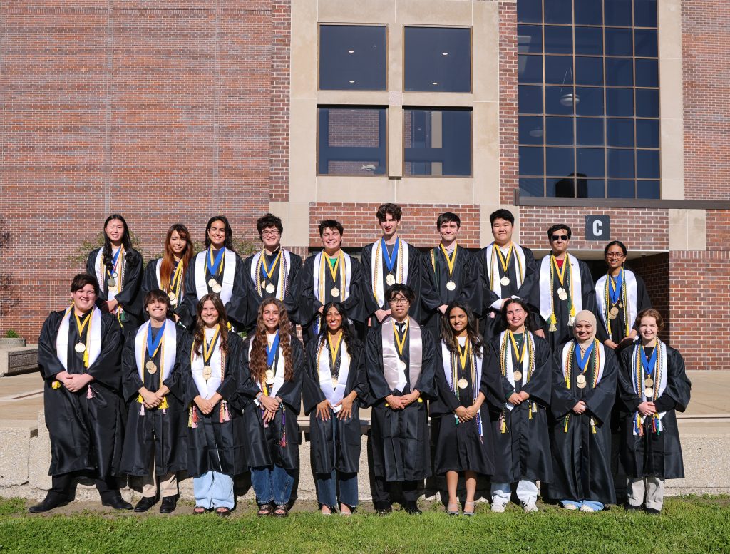 Graduates posing together in front of a building for a group photo.