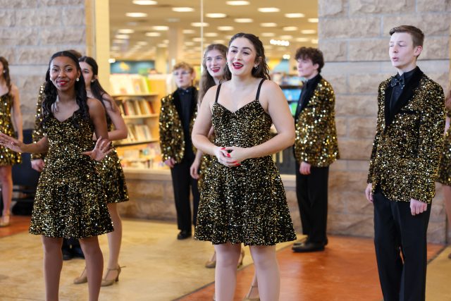A group of young people dressed in sequined costumes performing on a stage.
