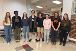 Group of young people posing for a photo in front of a school building.