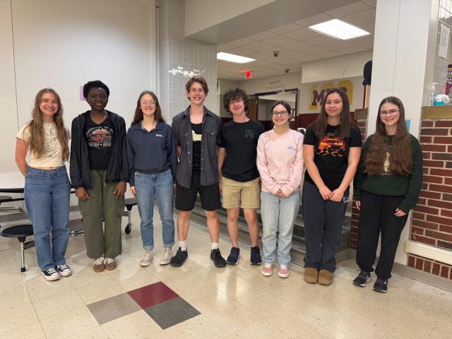 Group of young people posing for a photo in front of a school building.