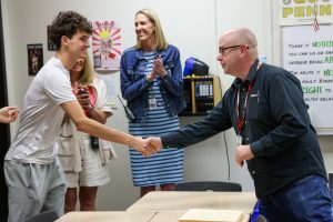 Two people shaking hands in a classroom setting.