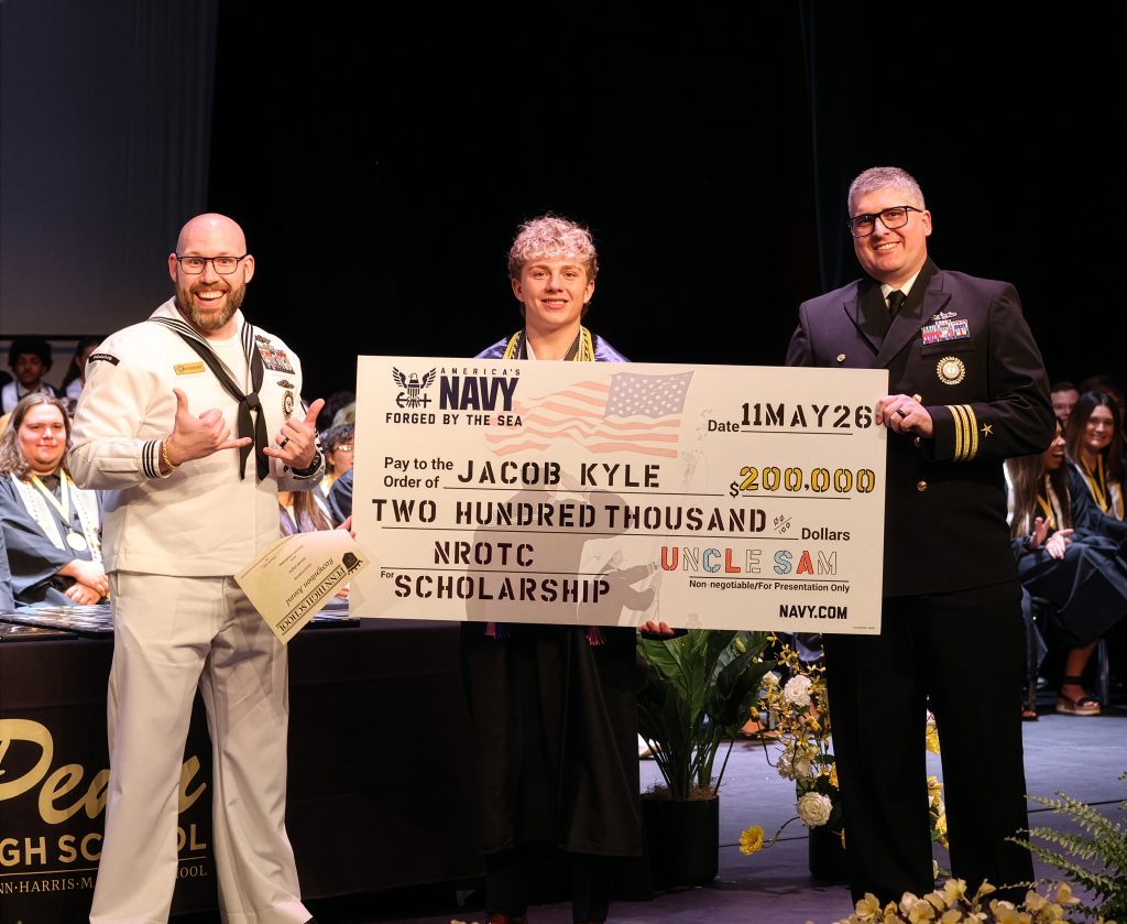 Two people standing next to a check, one of whom is holding a large check, posing for a photo at an event.