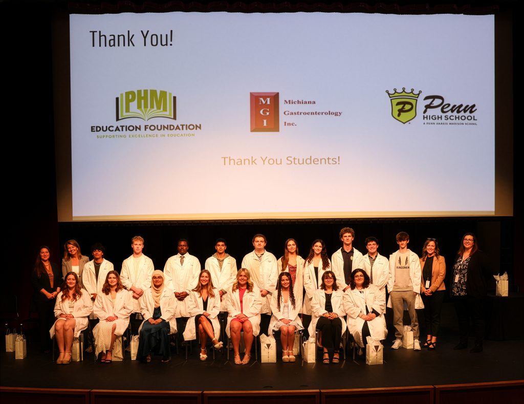 Students in white coats posing for a group photo at an event.