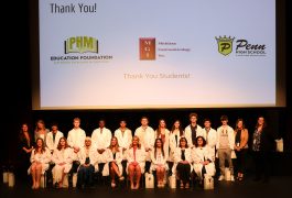Students in white coats posing for a group photo at an event.