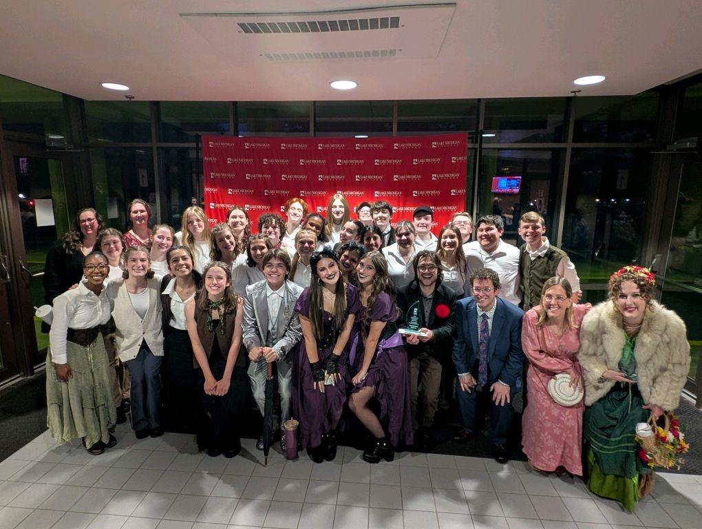 Group of people posing for a photo in front of a red banner.
