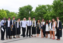Group of graduates posing together in front of a building.