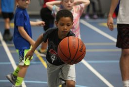 Boy in blue shirt dribbling basketball on court.