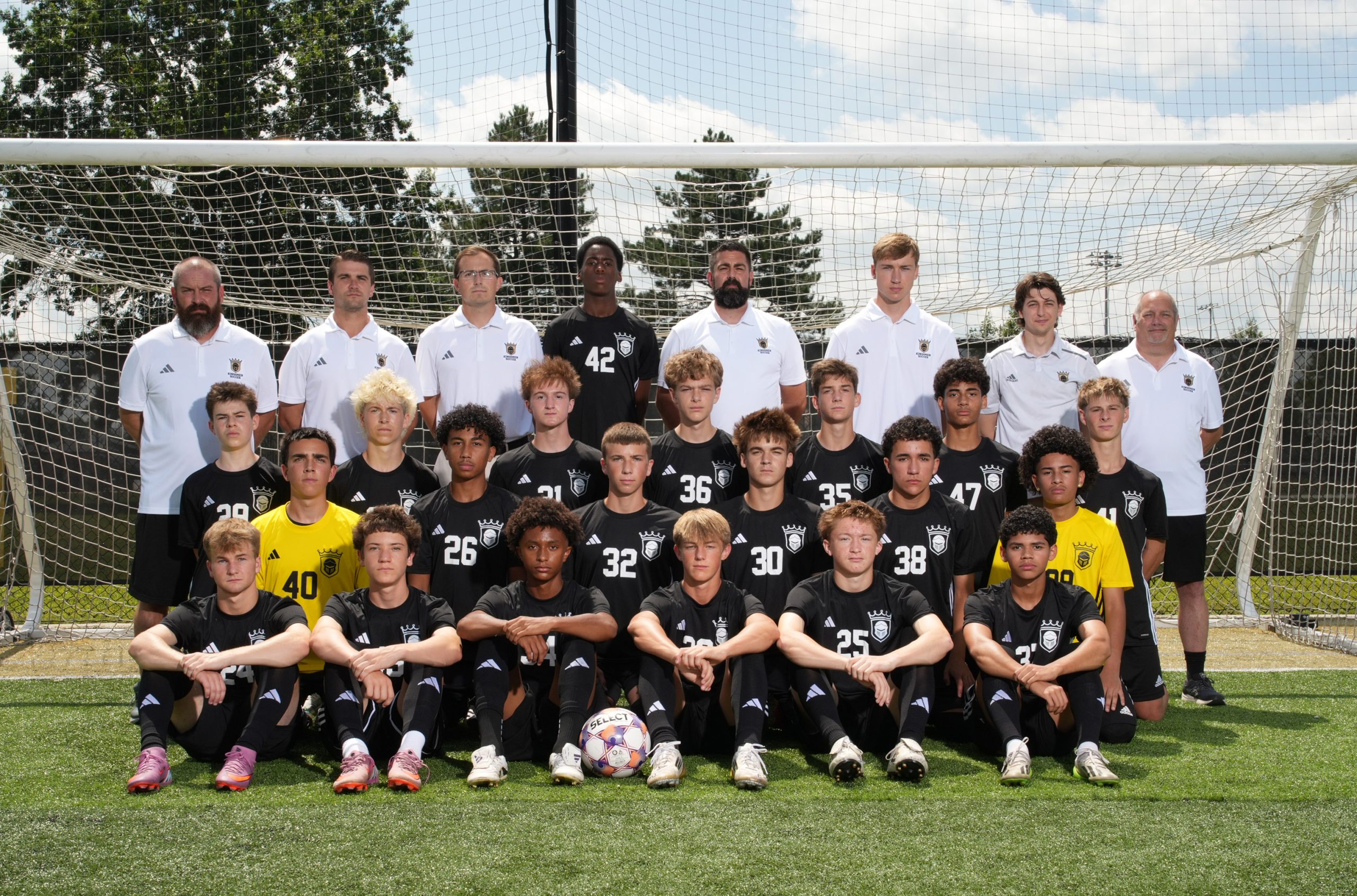 This is a team photo of a soccer team posing for a group picture in front of their goal net.