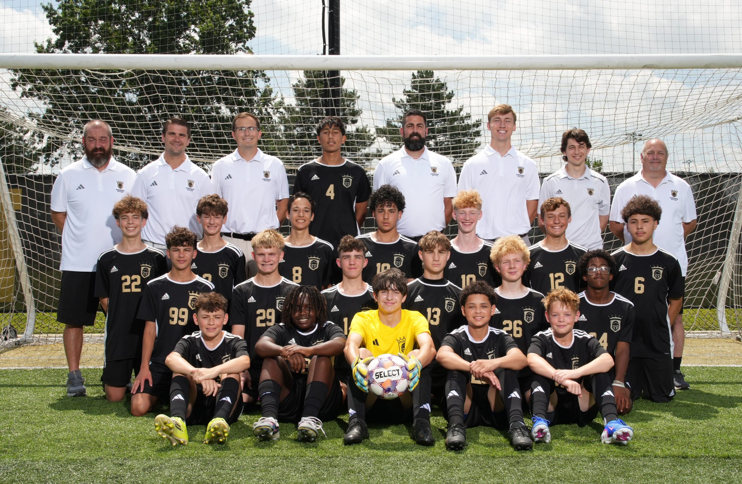 A soccer team posing for a group photo on a field.