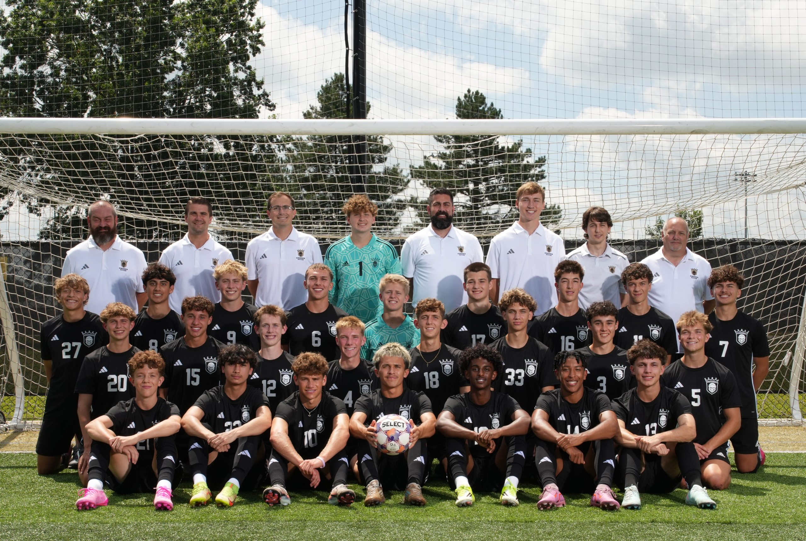 Soccer team posing for a group photo in front of their goal net