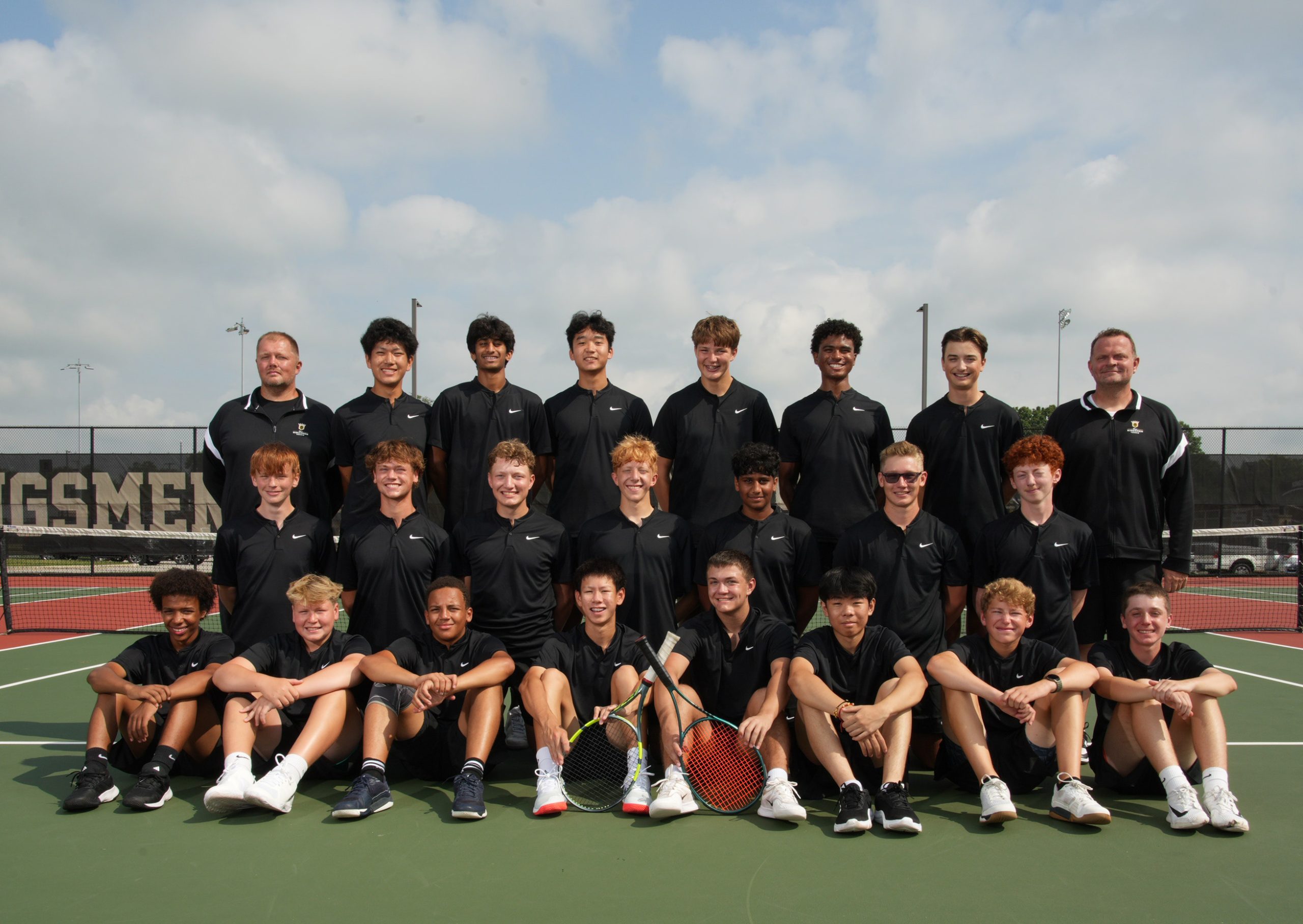 The team poses for a group photo on the tennis court.