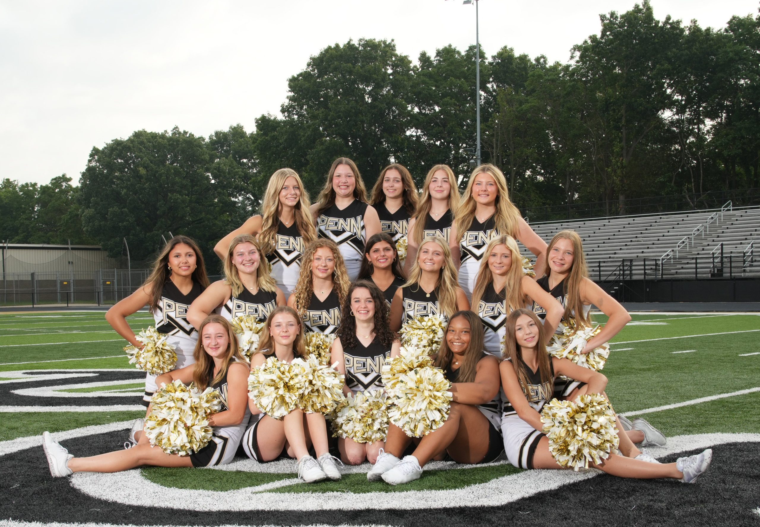 Cheerleaders posing for a team photo on a football field.
