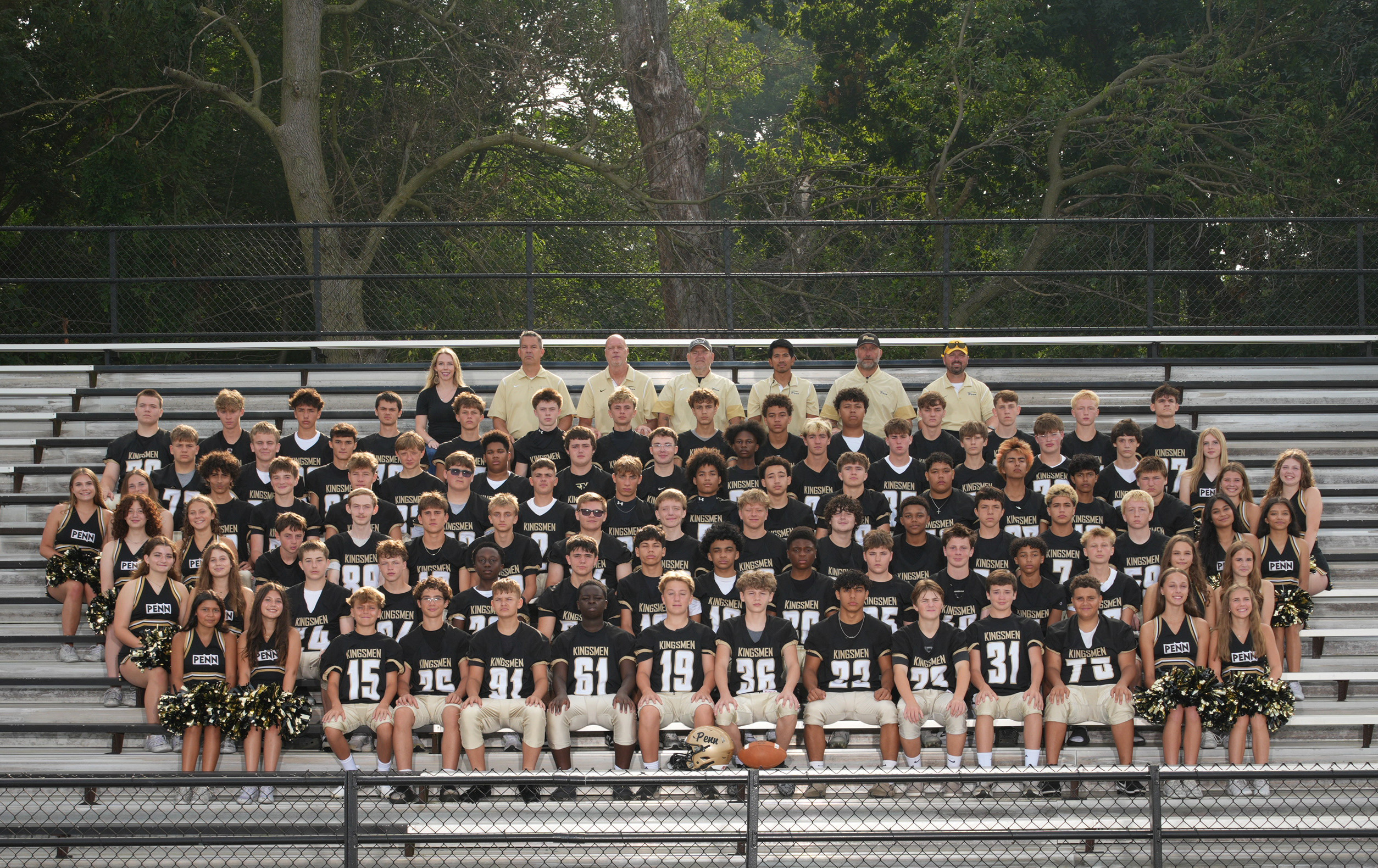 Football team posing in front of bleachers for a group photo.