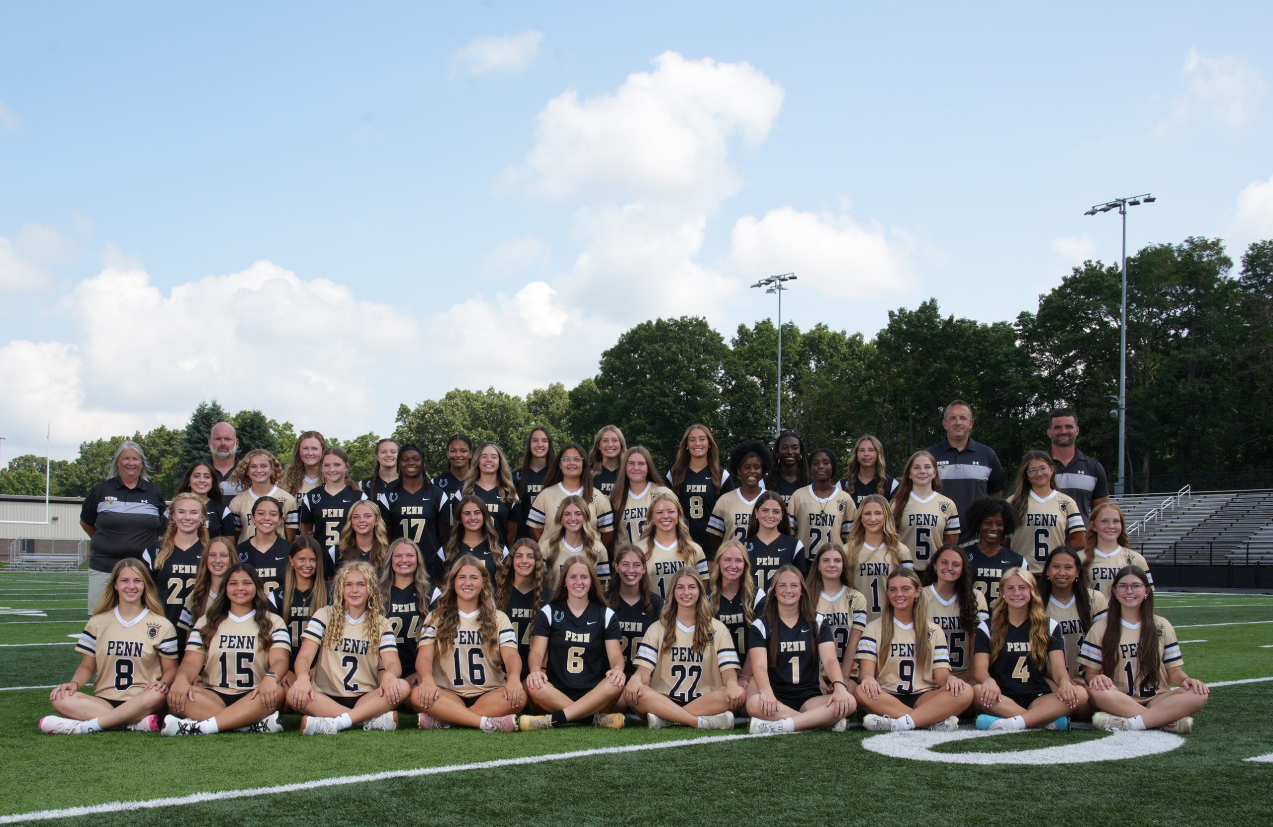 Team of young female athletes posing for a team picture on football field.