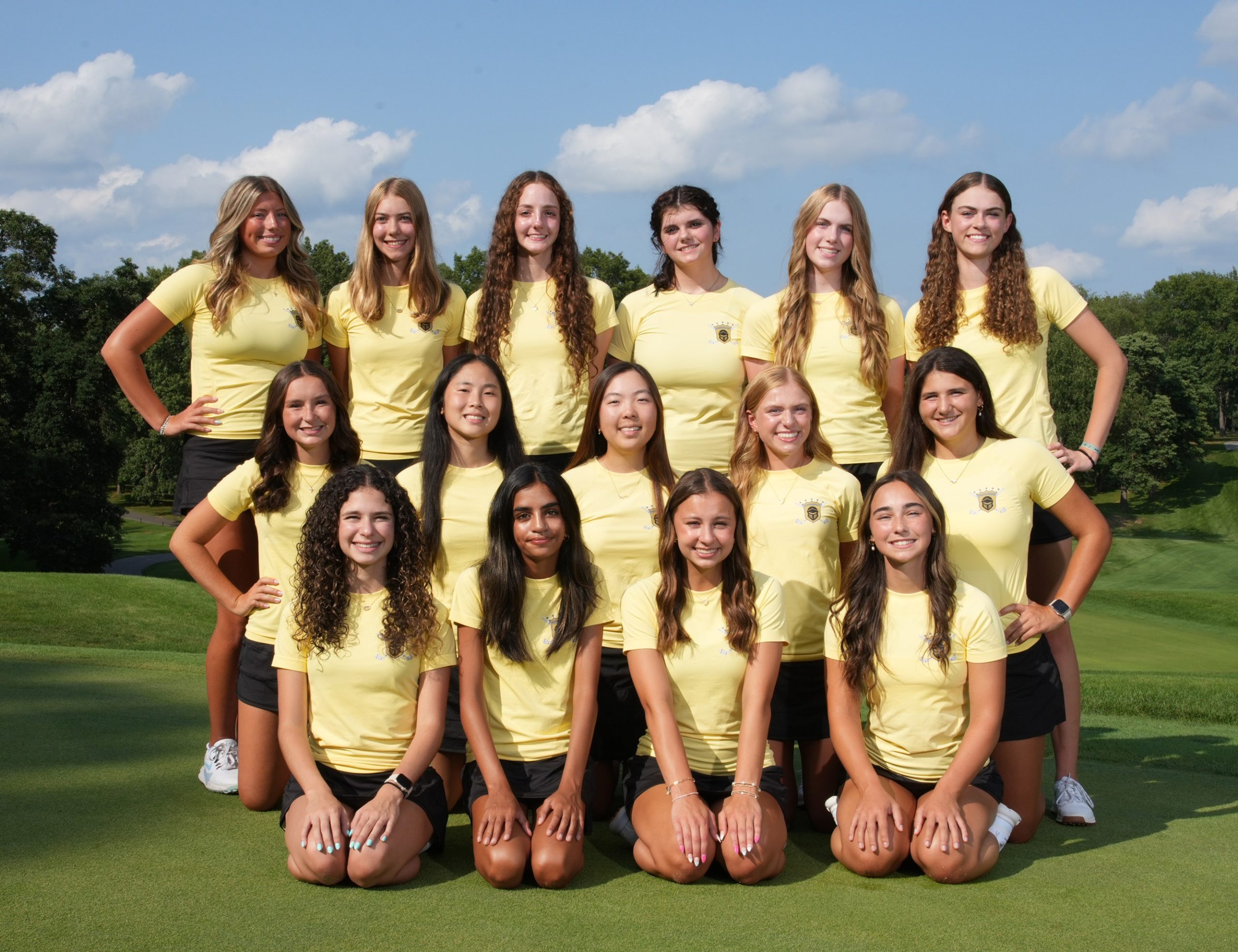 Team of female golfers posing for a team photo on a golf course.