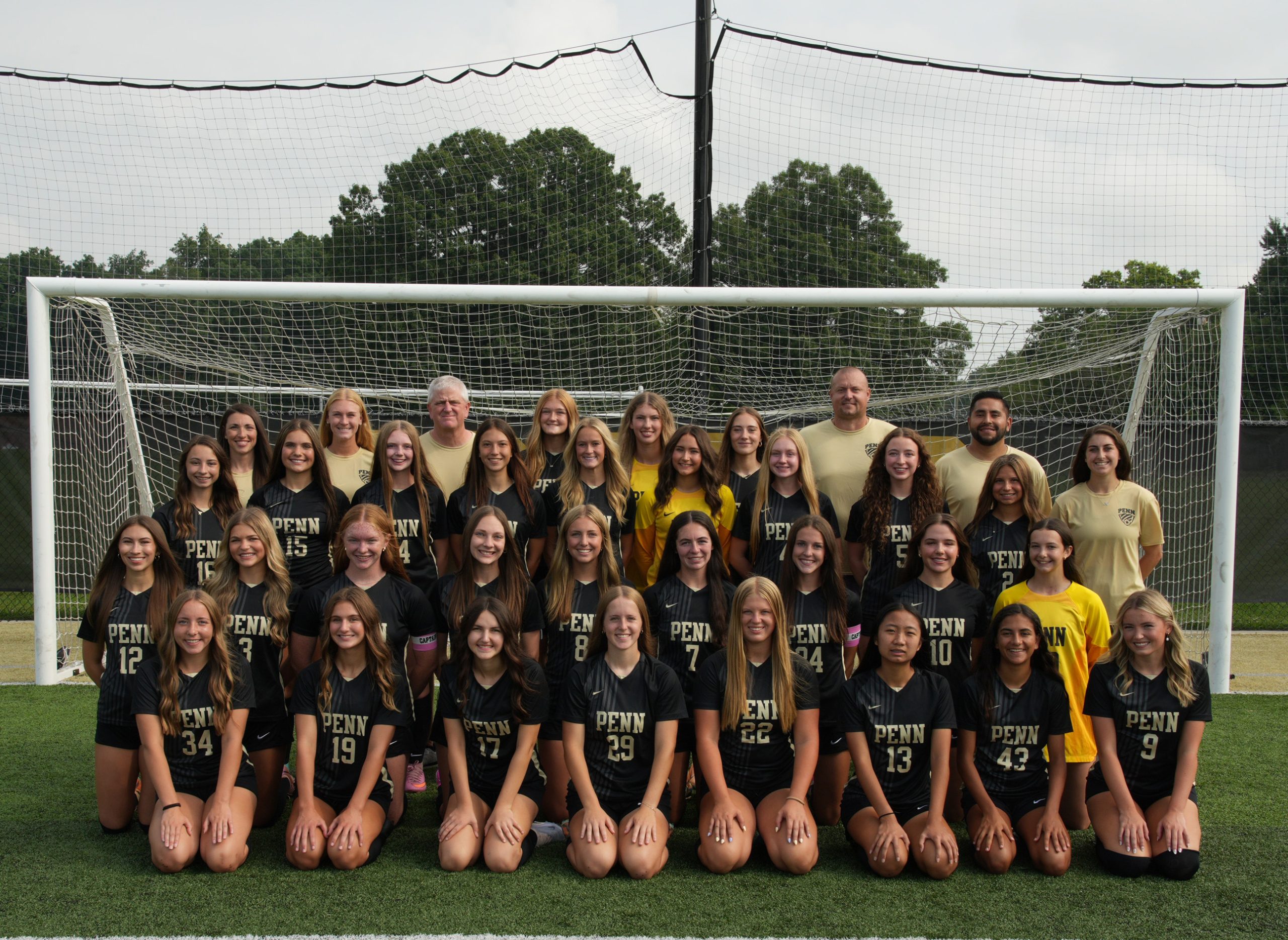 Team of girls soccer team posing for a group picture in front of goal.