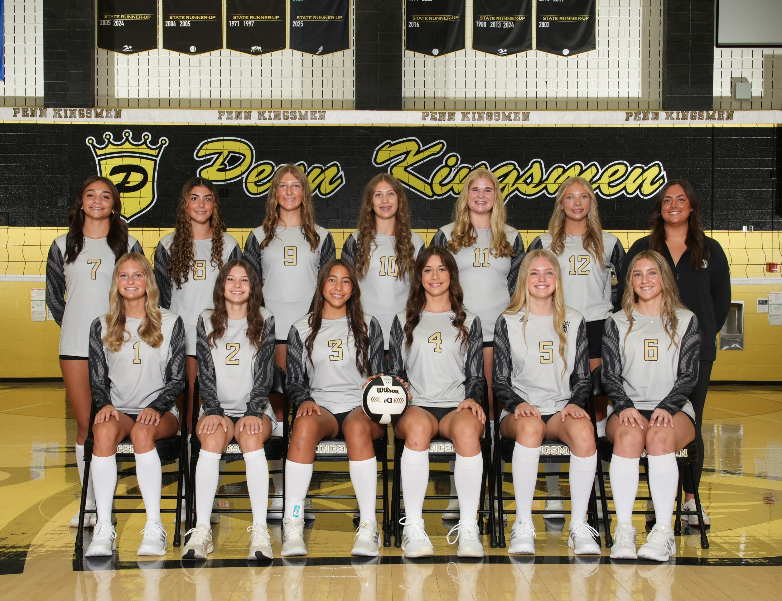 Girls' volleyball team posing for a group photo in their uniforms.