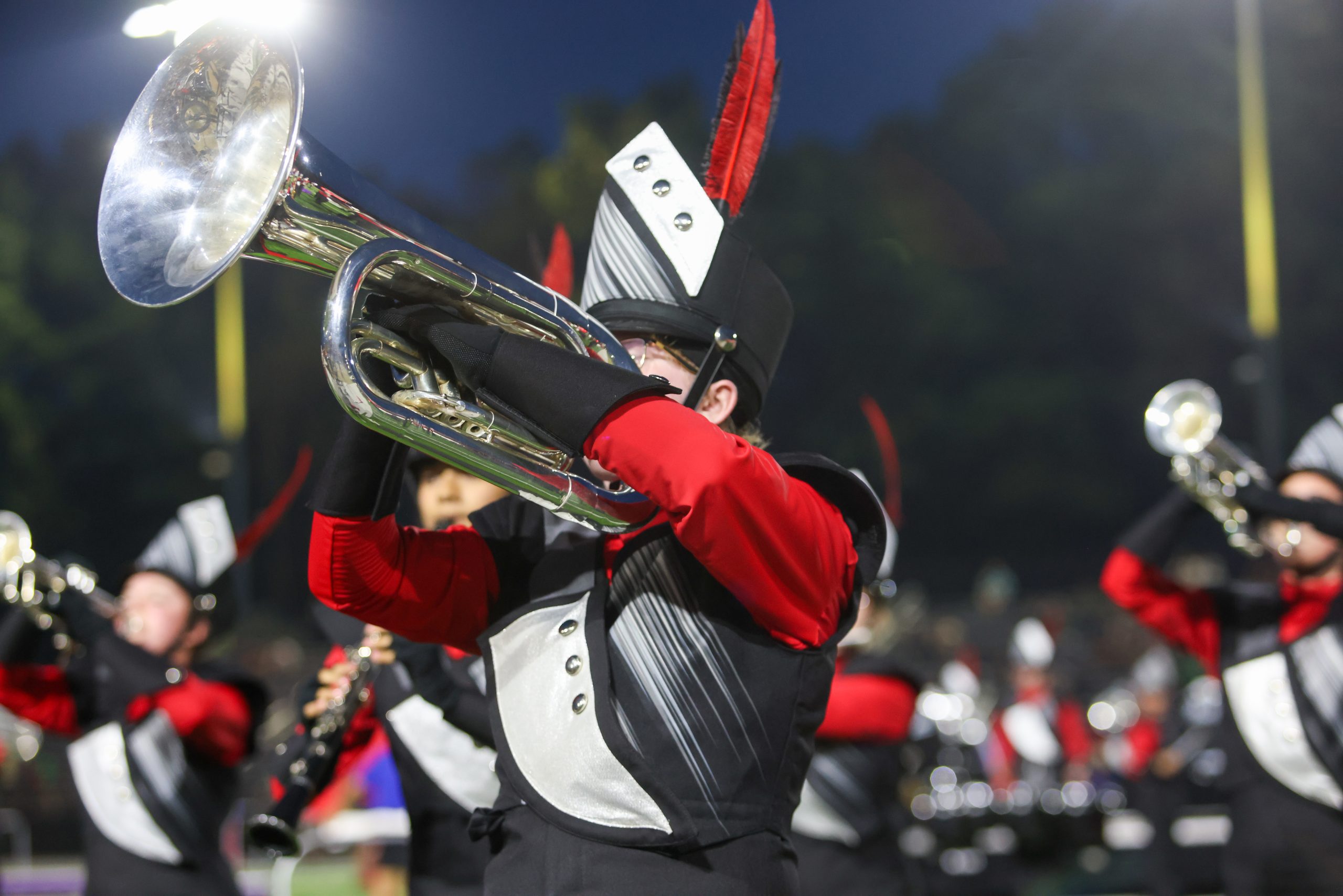 Marching band performing at night with illuminated instruments.
