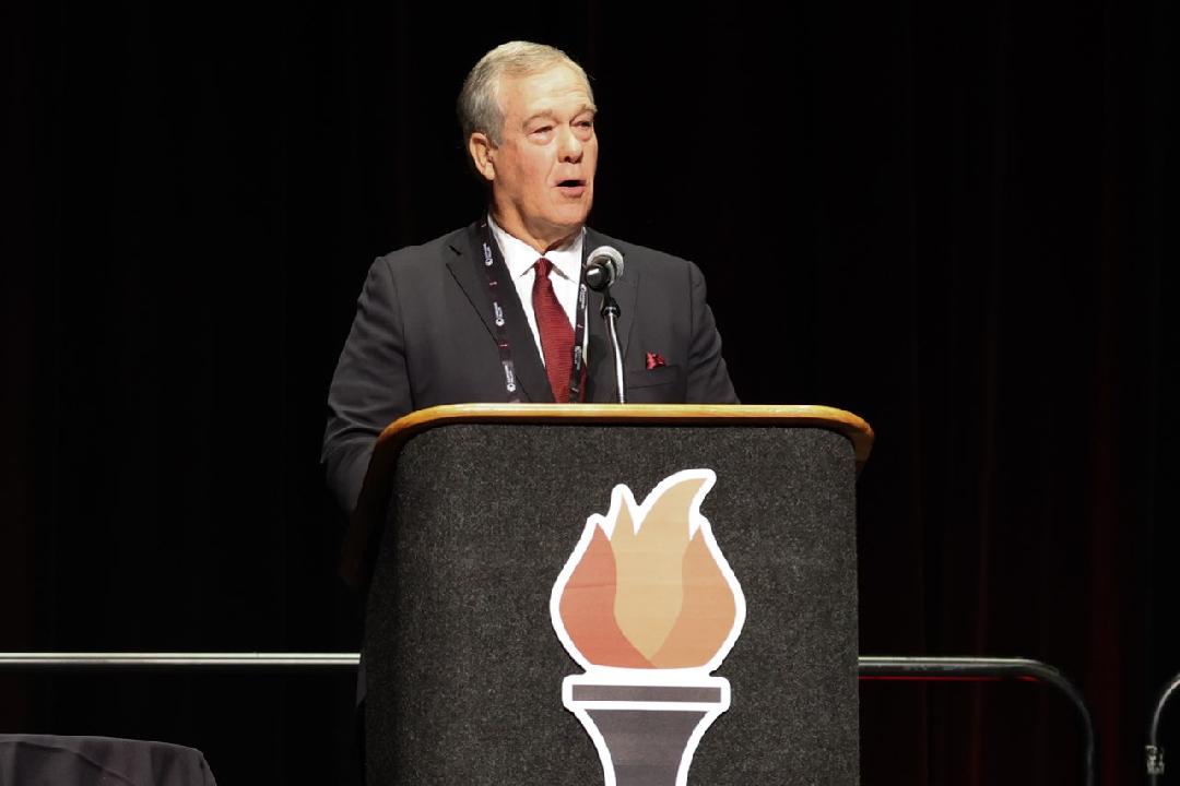 Man standing at podium, speaking at event.