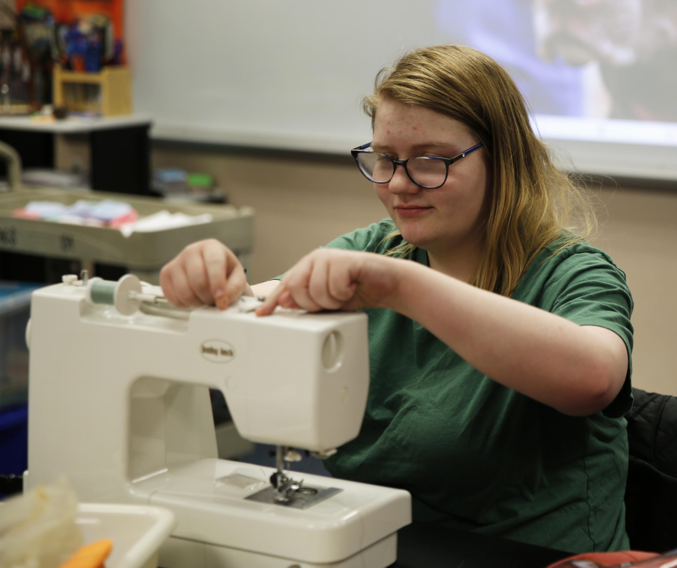 A girl sits at a sewing machine.