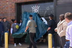 Group of people standing in front of a covered truck door.