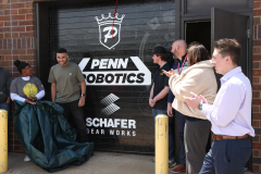 People standing outside a building with a sign that says "Penn Obotics" in the background.