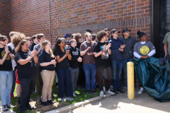 Group of people clapping in front of a building.