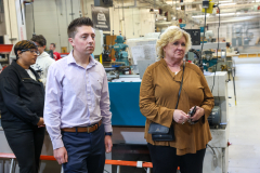 Two people standing in a factory setting, observing machinery.