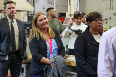 People in a workshop, observing something on a table.