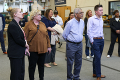People standing in a workshop, observing something on display.