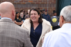 Woman in blue shirt standing between two men at an outdoor event.